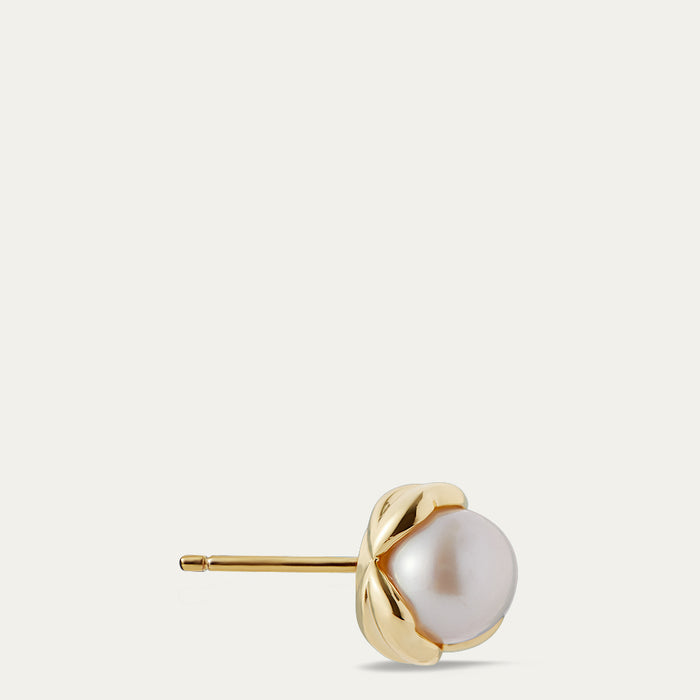 Gold stud earring with a pearl on a light beige background
