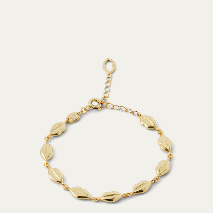 Gold bracelet with lip-shaped links on a light gray background