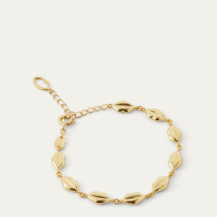 Gold bracelet with lip-shaped links on a light beige background