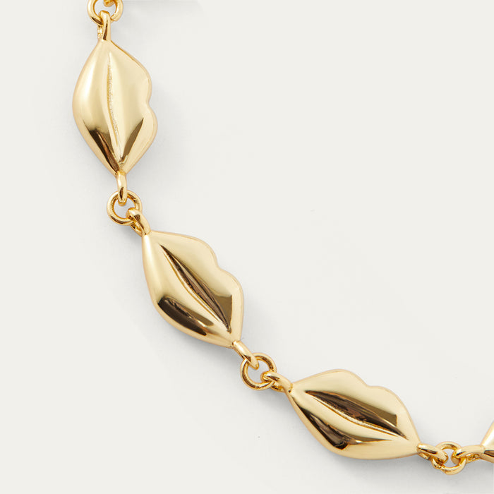 Gold bracelet with lip-shaped links on a light gray background