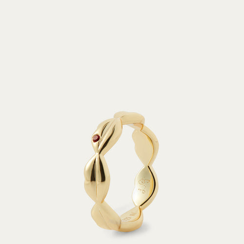 Gold ring with a small red gemstone on a light grey background