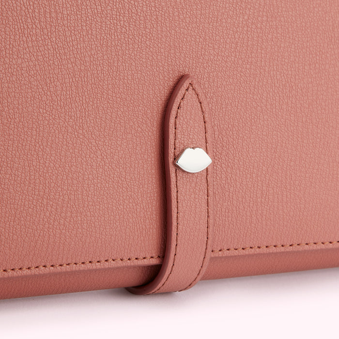 Close-up of a dusty rose-coloured leather wallet with a silver lip-shaped clasp.