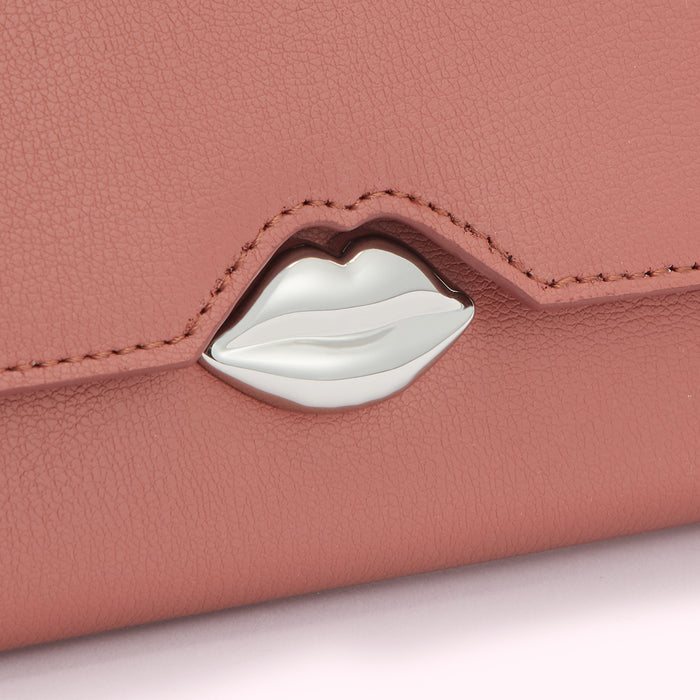 Close-up of a dusty rose-coloured wallet with a silver lip-shaped clasp.