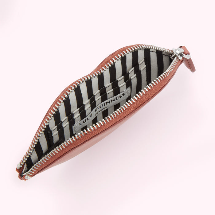 Open terracotta Lulu Guinness lip-shaped coin purse with black and white striped interior.