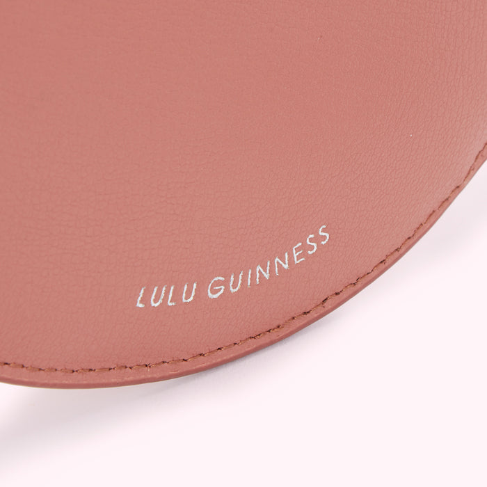 Close-up of a dusty rose Lulu Guinness handbag, showing the brand name subtly embossed on the leather.