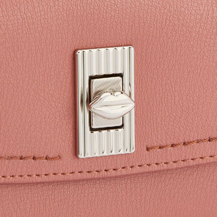 Close-up of a dusty rose handbag's clasp, featuring a lip-shaped detail.