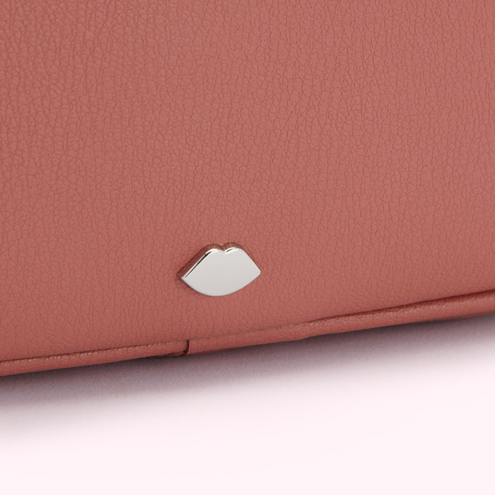Close-up of a dusty rose-coloured purse with a silver lip-shaped emblem.
