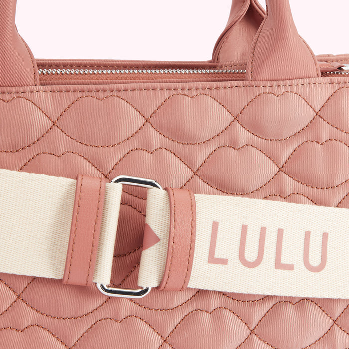 Close-up of a dusty rose Lulu Guinness quilted handbag with a cream and rose-coloured strap.