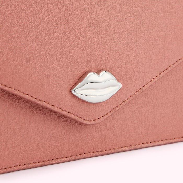Close-up of a dusty rose leather wallet with a silver lip-shaped detail.