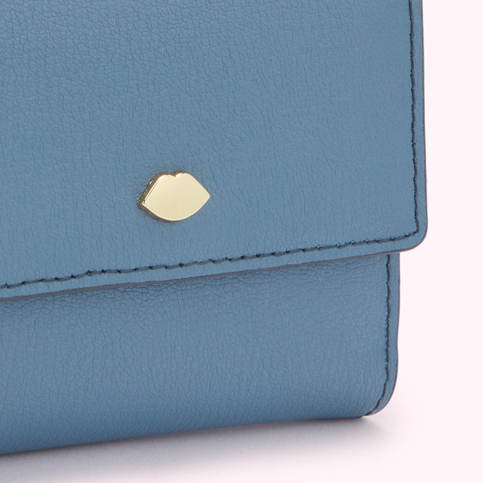 Close-up of a blue leather wallet with a gold lip-shaped detail.