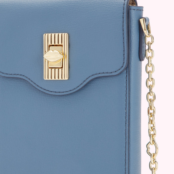 Close-up of a blue leather crossbody bag with a gold lip-shaped clasp and chain strap.