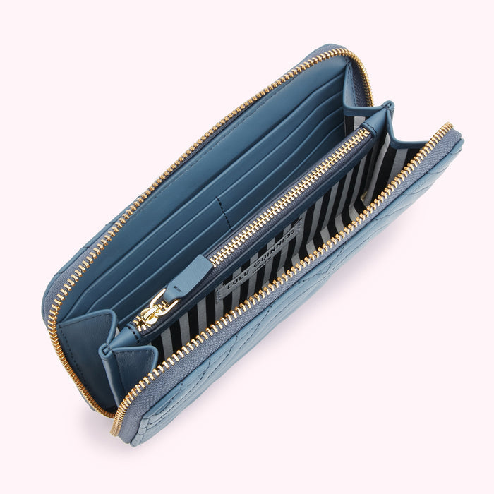 Open blue quilted zip-around wallet by Lulu Guinness, showcasing the interior compartments and gold zippers.