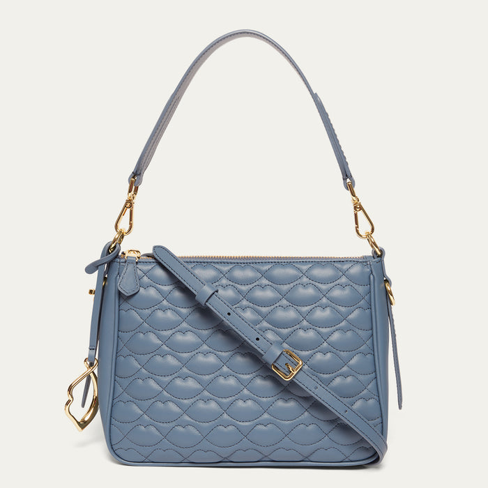 Blue quilted handbag with gold accents on a light gray background