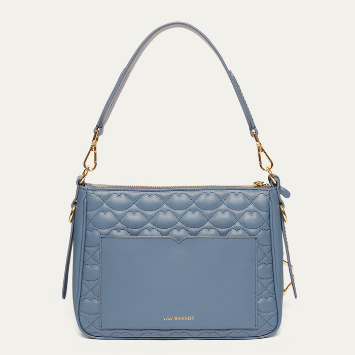 Blue quilted handbag with gold accents on a light gray background
