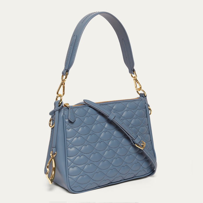 Blue quilted handbag with gold accents on a light gray background