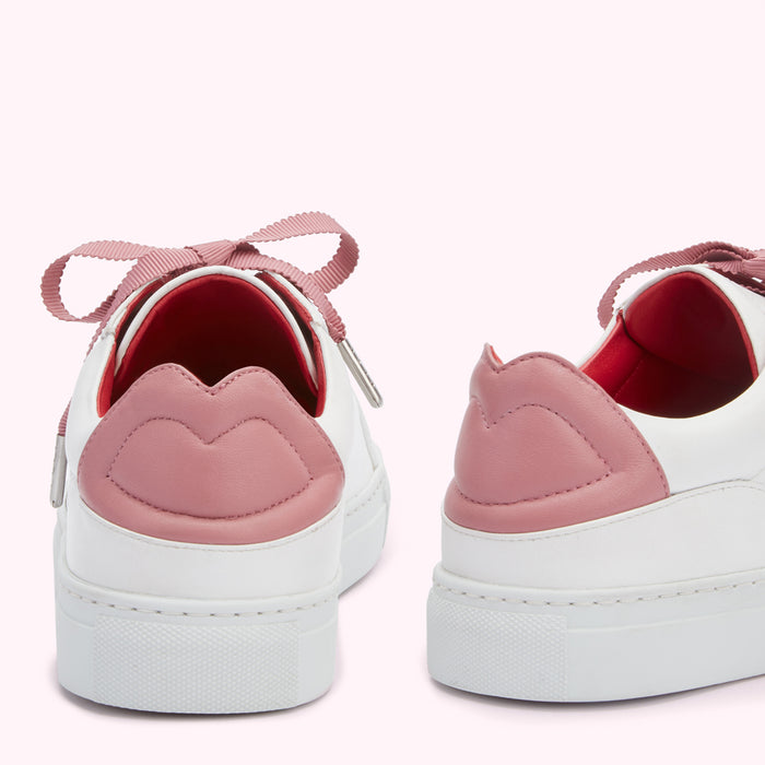Rear view of a pair of white leather sneakers with pink lip-shaped detailing on the heel, tied with pink ribbon laces.