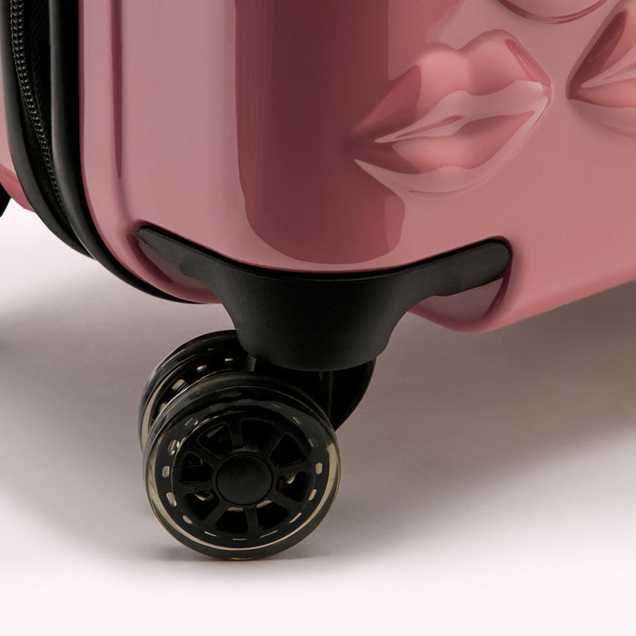 Close-up of the wheels and bottom of a pink carry-on suitcase with lips design.