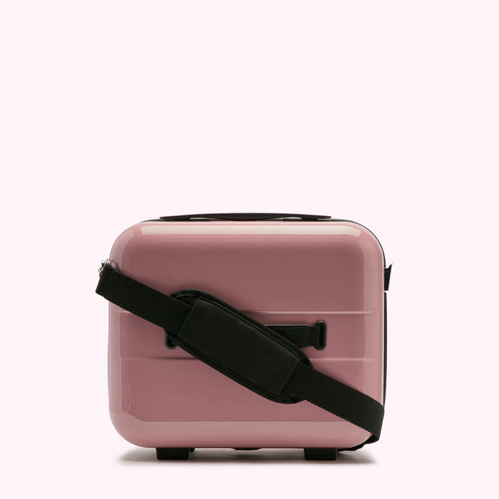 Pink carry-on suitcase with a black shoulder strap against a white background.