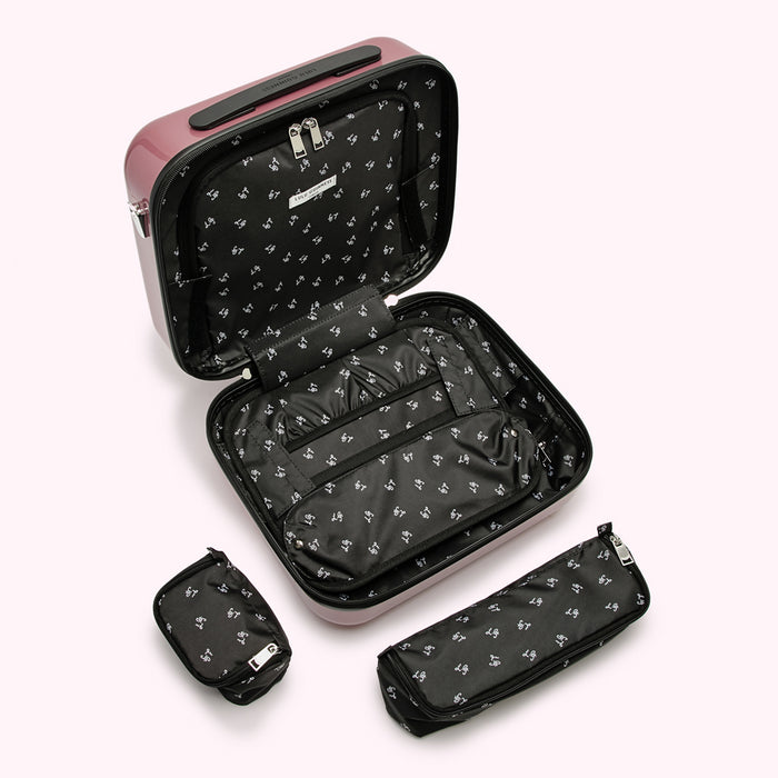 A mauve pink carry-on suitcase with its interior compartments and matching accessories open, showing its organization.