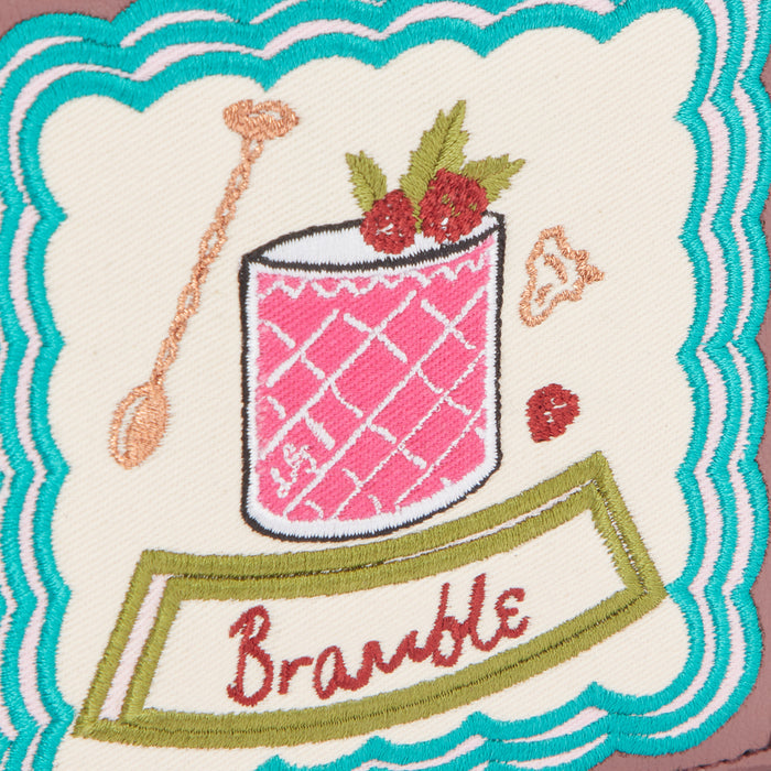 Embroidered patch of a Bramble cocktail on an off-white background with teal and mauve stitching.