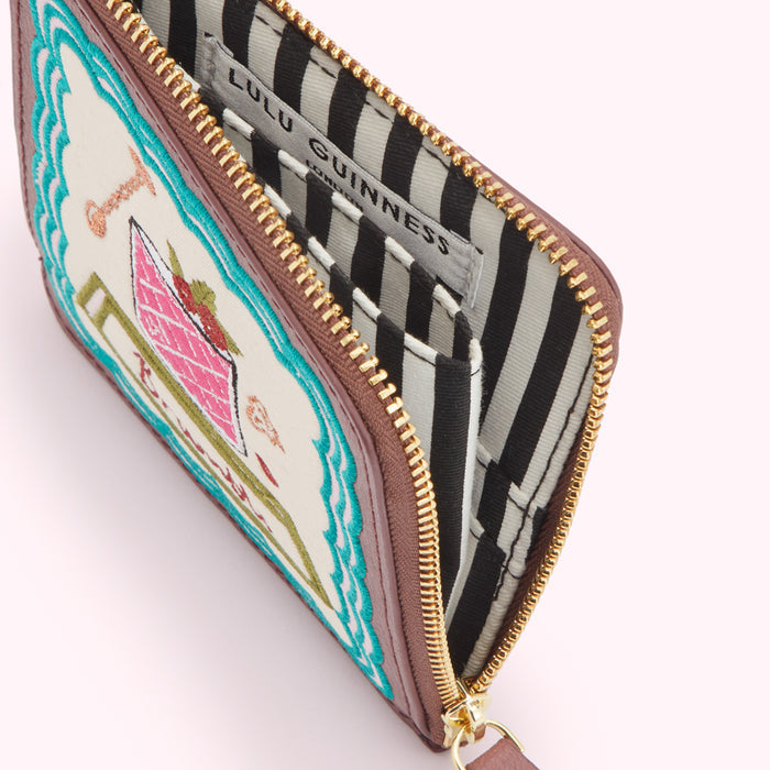 Open Lulu Guinness zip-around purse with embroidered cocktail design and black and white striped interior.