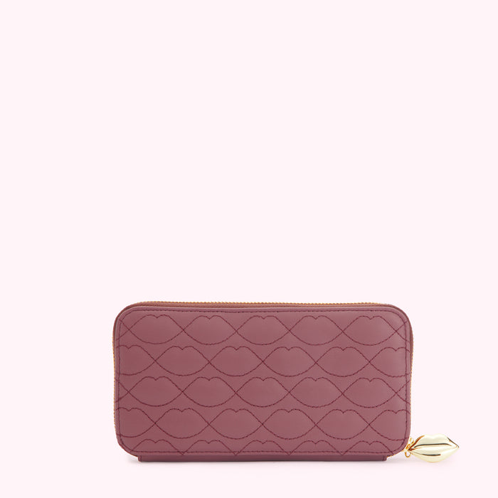 A mauve quilted zip-around wallet with a lip print and gold zipper and charm.