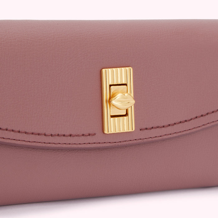 Close-up of a mauve leather wallet with a gold lip-shaped clasp.