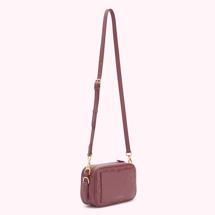 A dusty rose quilted crossbody bag with gold hardware.