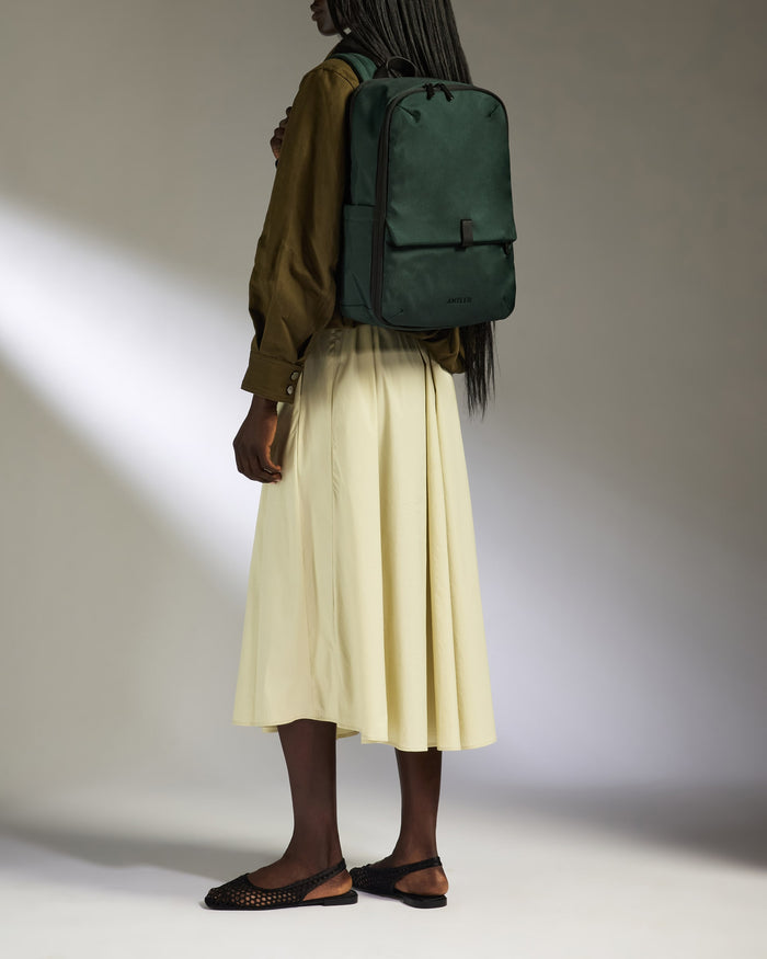 a woman wearing a white skirt and a green backpack