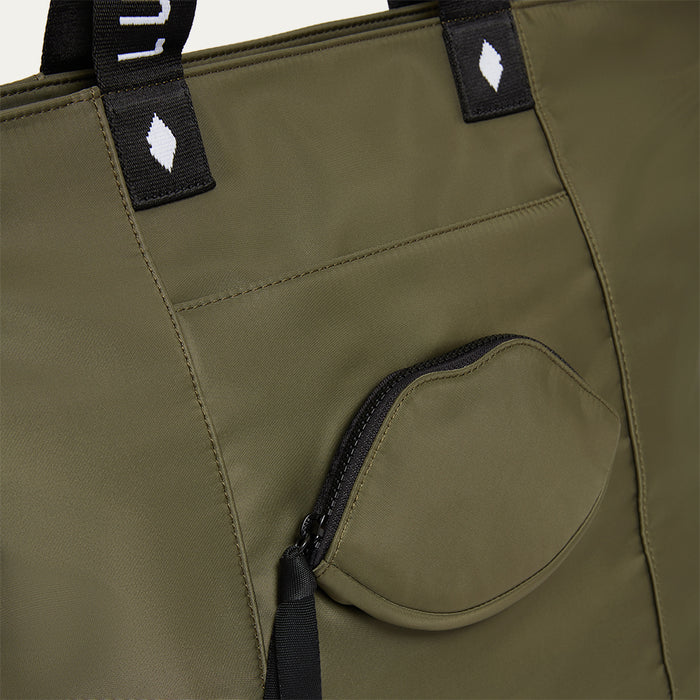 Close-up of a green bag with a lip-shaped pocket and black straps on a white background