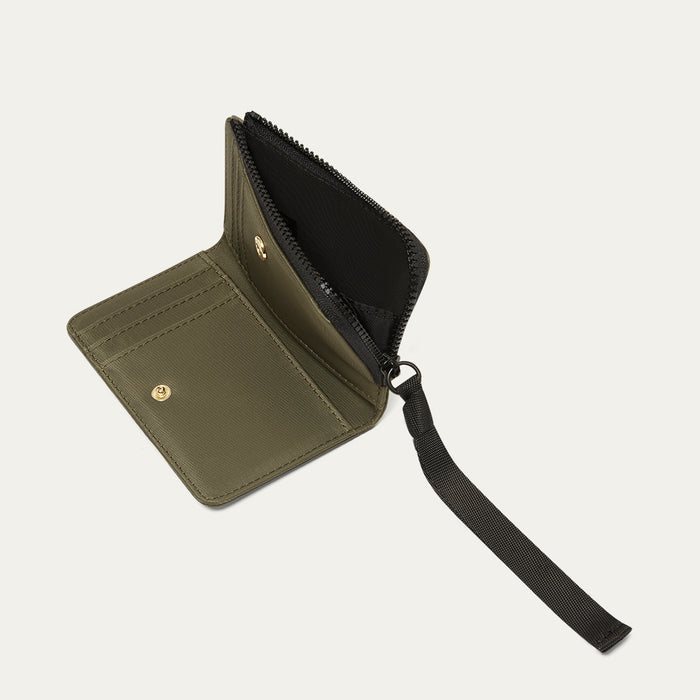 Green wallet with a black ribbon zip pull , open on a light grey background