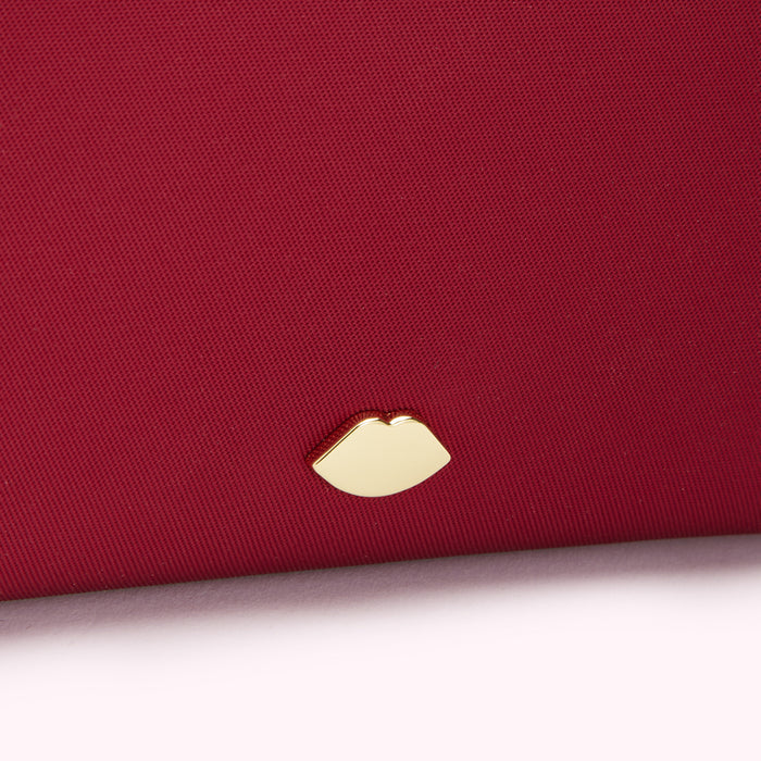 Close-up of a dark red textured surface with a gold lip-shaped emblem.