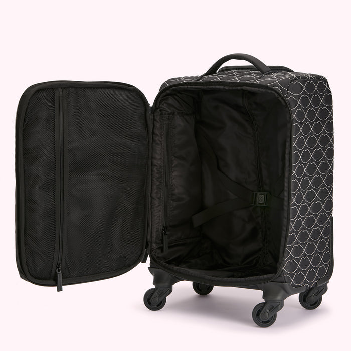Open black rolling suitcase with white lip print and multiple compartments.