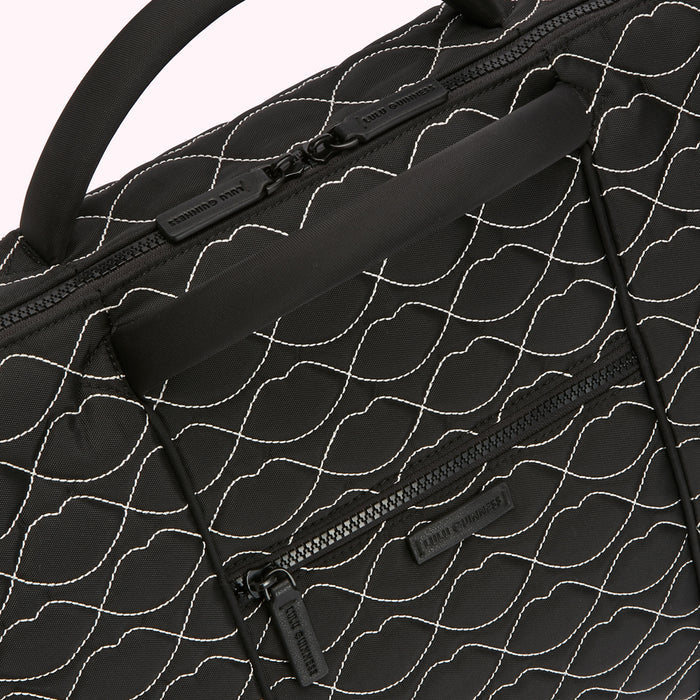 Close-up of a black Lulu Guinness quilted bag with a white lip pattern and top handle.