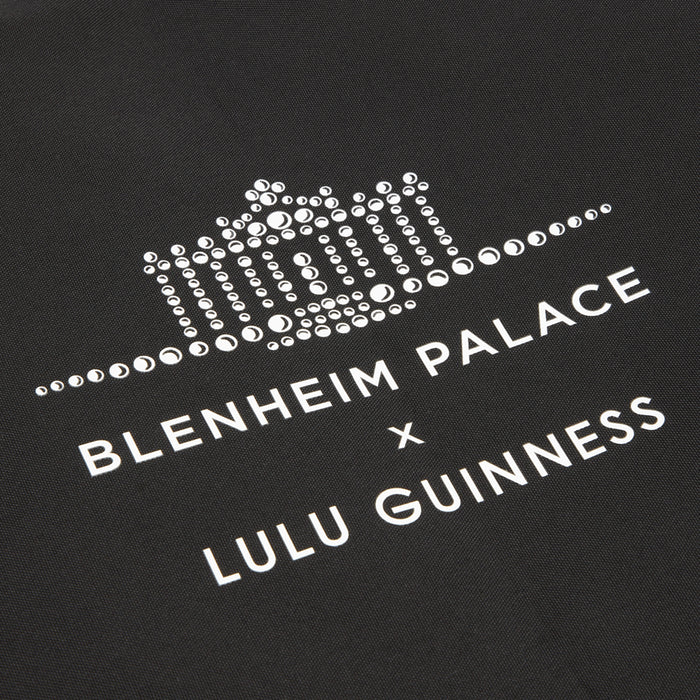 Black tote bag with white text and graphic: "Blenheim Palace x Lulu Guinness". The Blenheim Palace graphic is represented by small circles resembling rhinestones.