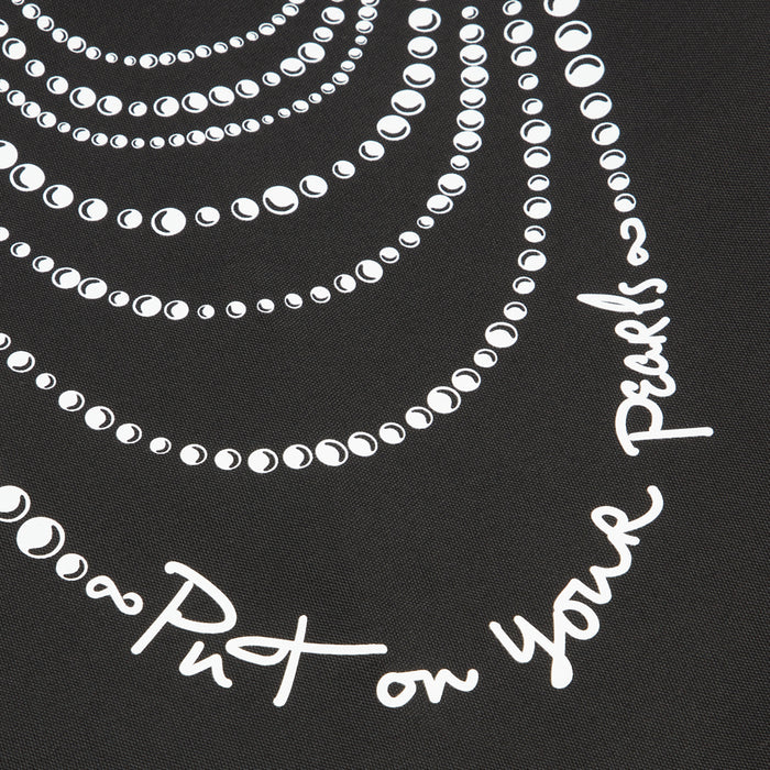 Close-up of a black textile with a design of white pearl necklaces and the text "Put on your Pearls".