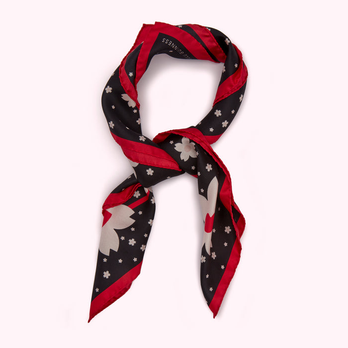 Black silk scarf with a red border and a pattern of light grey flowers.