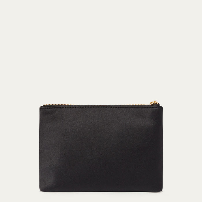 Black satin pouch with a gold zipper on a light beige background