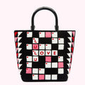Black and white crossword-style tote bag with pink accents and red "LOVE LULU" lettering against a white background.