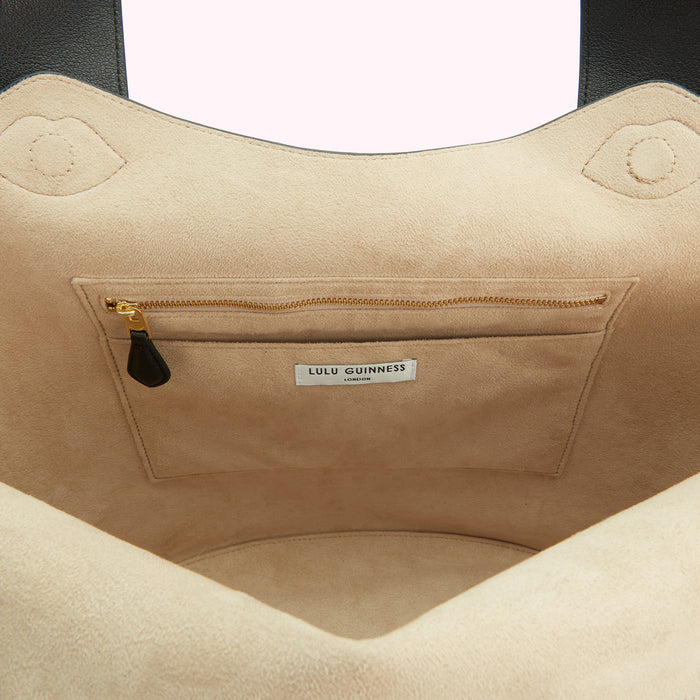 Inside of a beige Lulu Guinness London tote bag showing a zippered pocket and brand label.