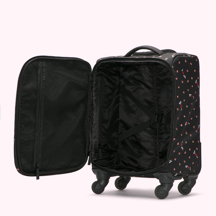 Open black suitcase with pink and white design, showing interior compartments and wheels.