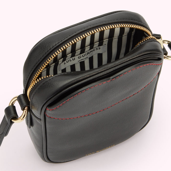 Image of a black leather crossbody bag with contrasting red lip shaped stitching on the front pocket open revealing an inside slip pocket and striped white and black lining.