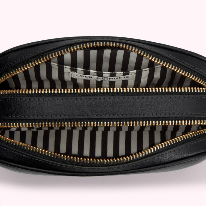 Inside of a black Lulu Guinness handbag with gold zippers and a black and white striped lining.
