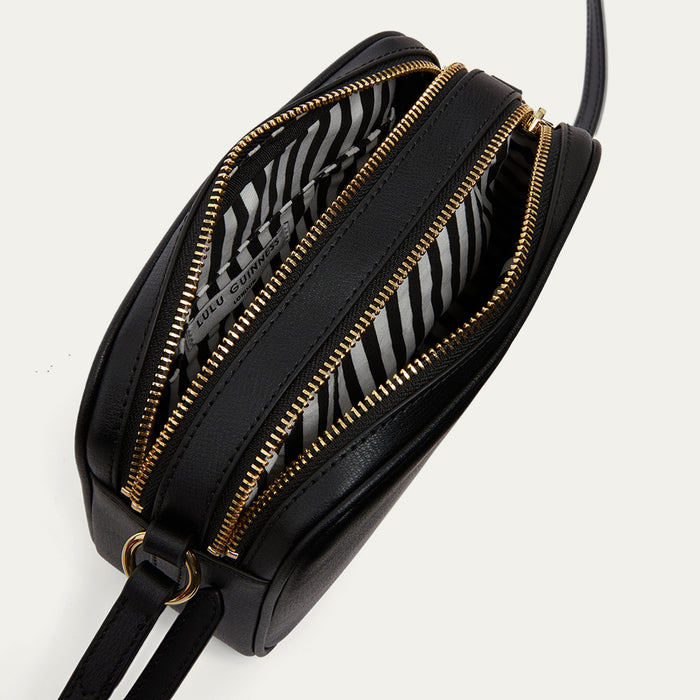 Black handbag with gold zippers on a light gray background