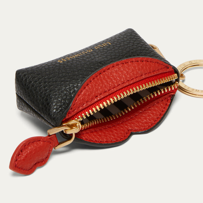 A small pouch in black pebbled leather with a bright red interior and gold-tone hardware, shown open on a light gray background.
