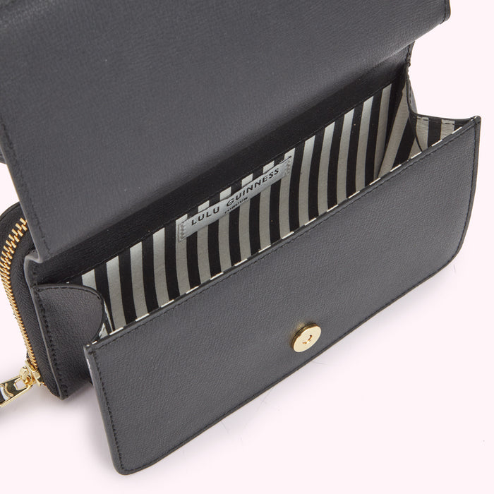 Inside image of a black leather bag pocket showing a striped black and white lining and magnetic fastening.