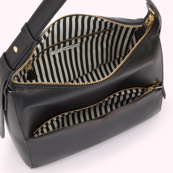 Inside image of a black leather shoulder bag open revealing a striped black and whtie lining and inside zip pocket.