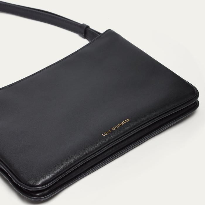 Black handbag with 'Lulu Guinness' branding on a light gray background
