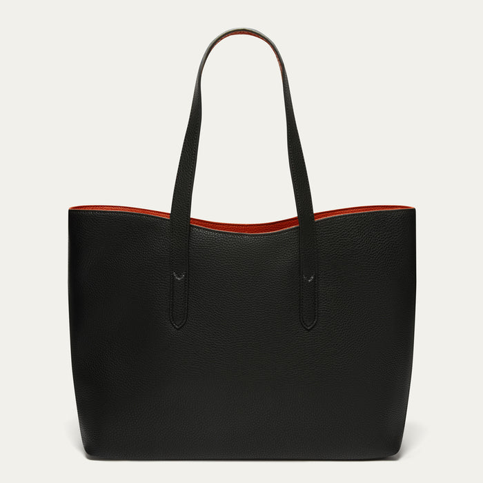 A black pebbled leather tote bag with dual shoulder straps and a contrasting red interior lining, shown against a plain off-white background.