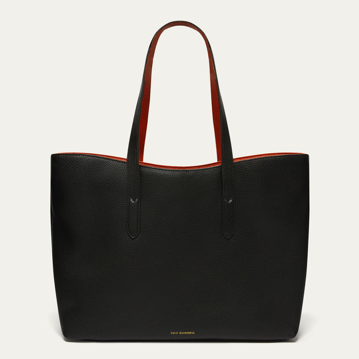 A black pebbled leather tote bag with contrasting red interior lining and red handles, shown against a light off-white background. The brand name 'LULU GUINNESS' is subtly printed in gold at the bottom center.
